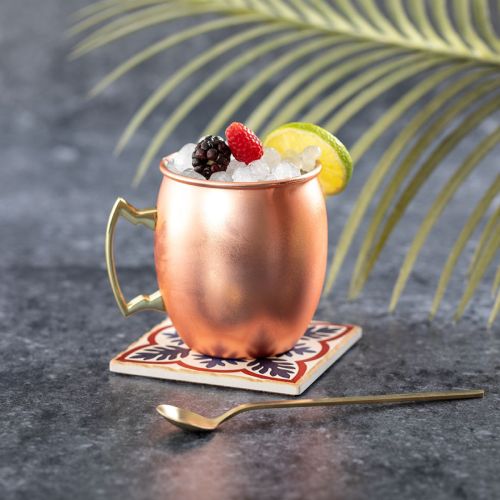 Gevulde Moscow Mule beker van RVS in sfeerruimte, weergegeven als drankbeker in gebruik.