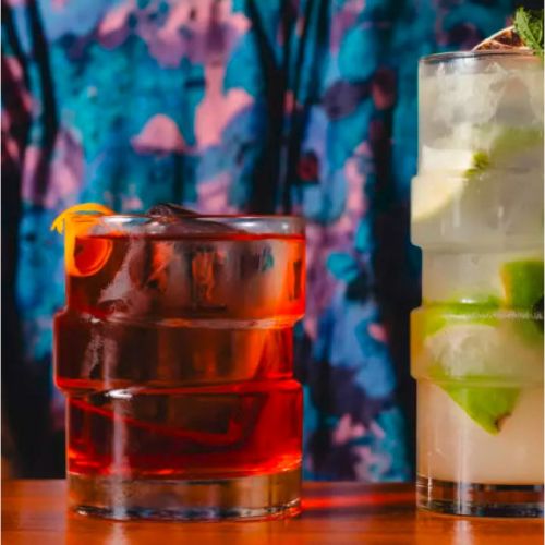 The Glitch tumbler glas 35,5 cl. gevuld met drank, geplaatst in sfeervolle omgeving.