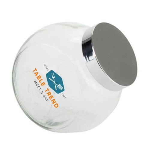 Snoeppot van glas met zilverkleurig deksel en meerkleurig TableTrend-logo op de voorzijde aangebracht.